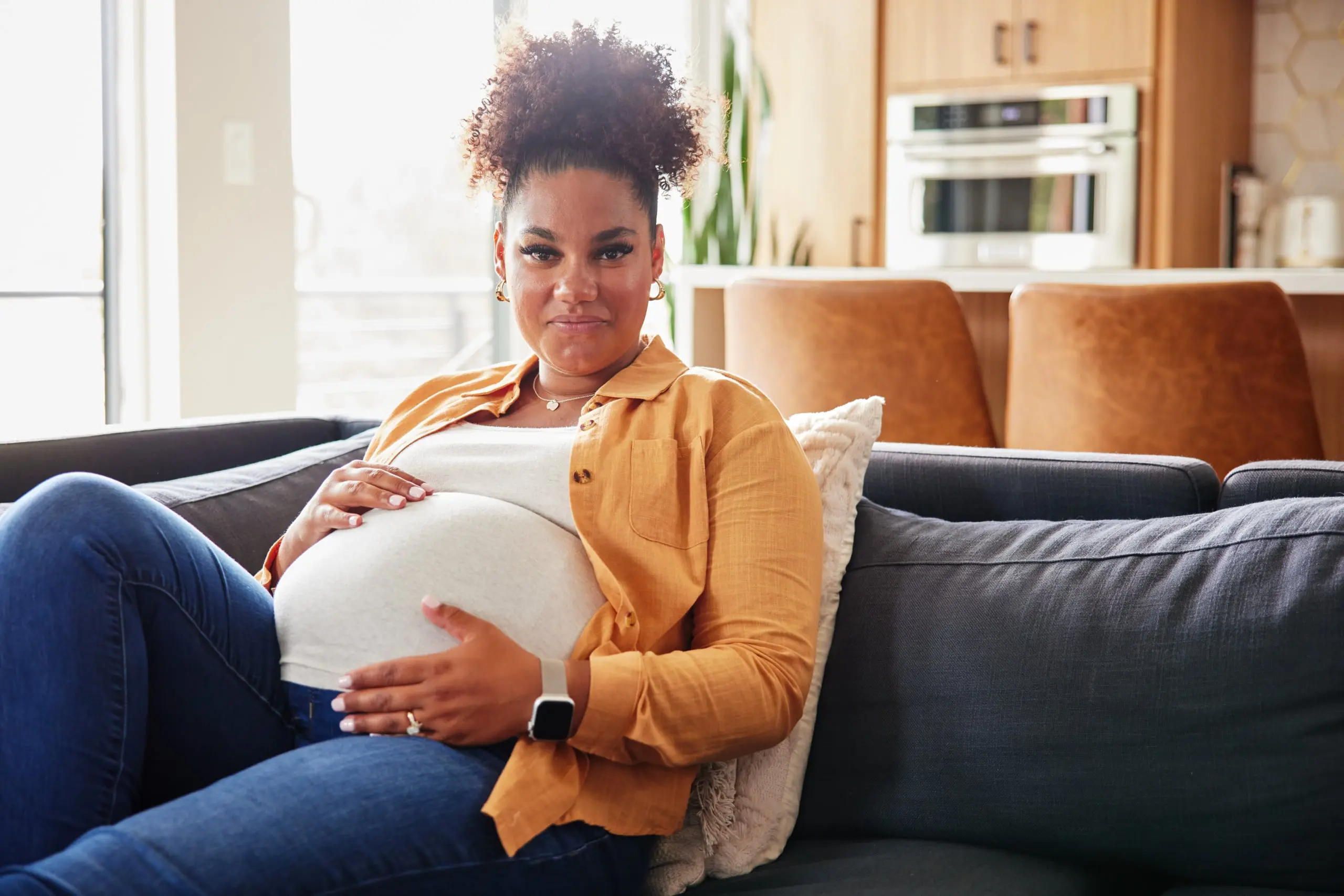 Pregnant mother on couch holding her stomach