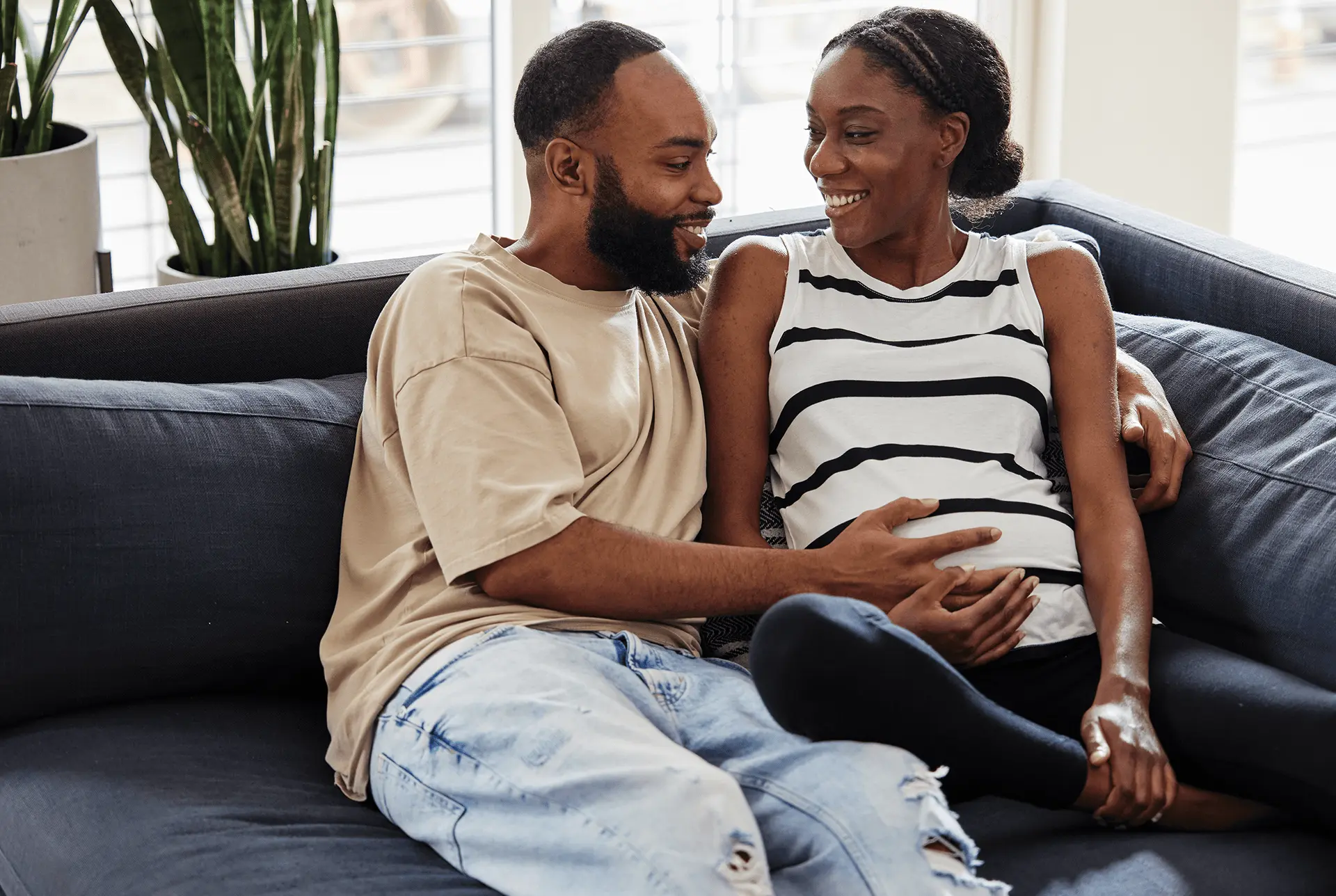 Man and wife on couch holding wife's pregnant stomach