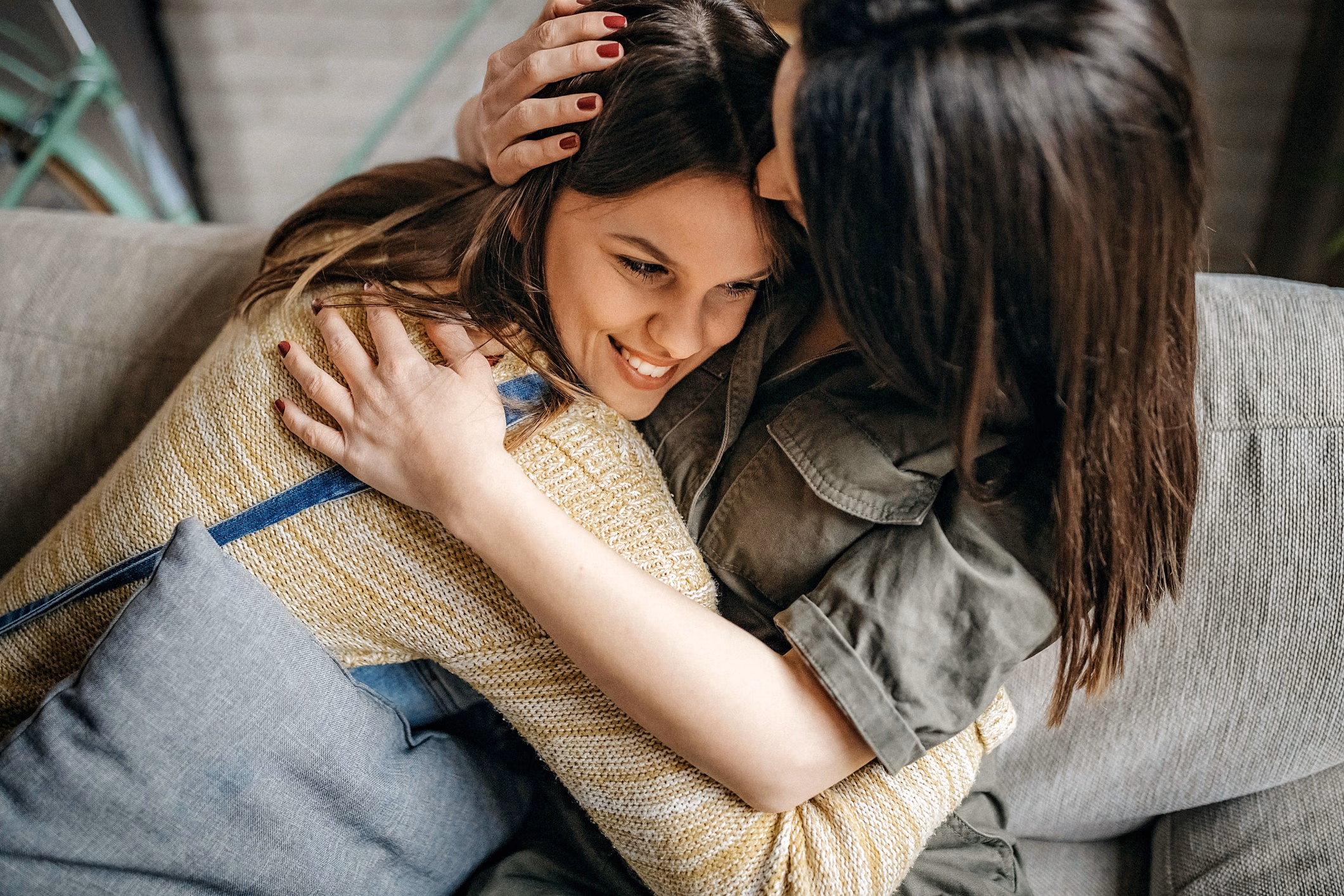 Mother and daughter hugging on a gray couch