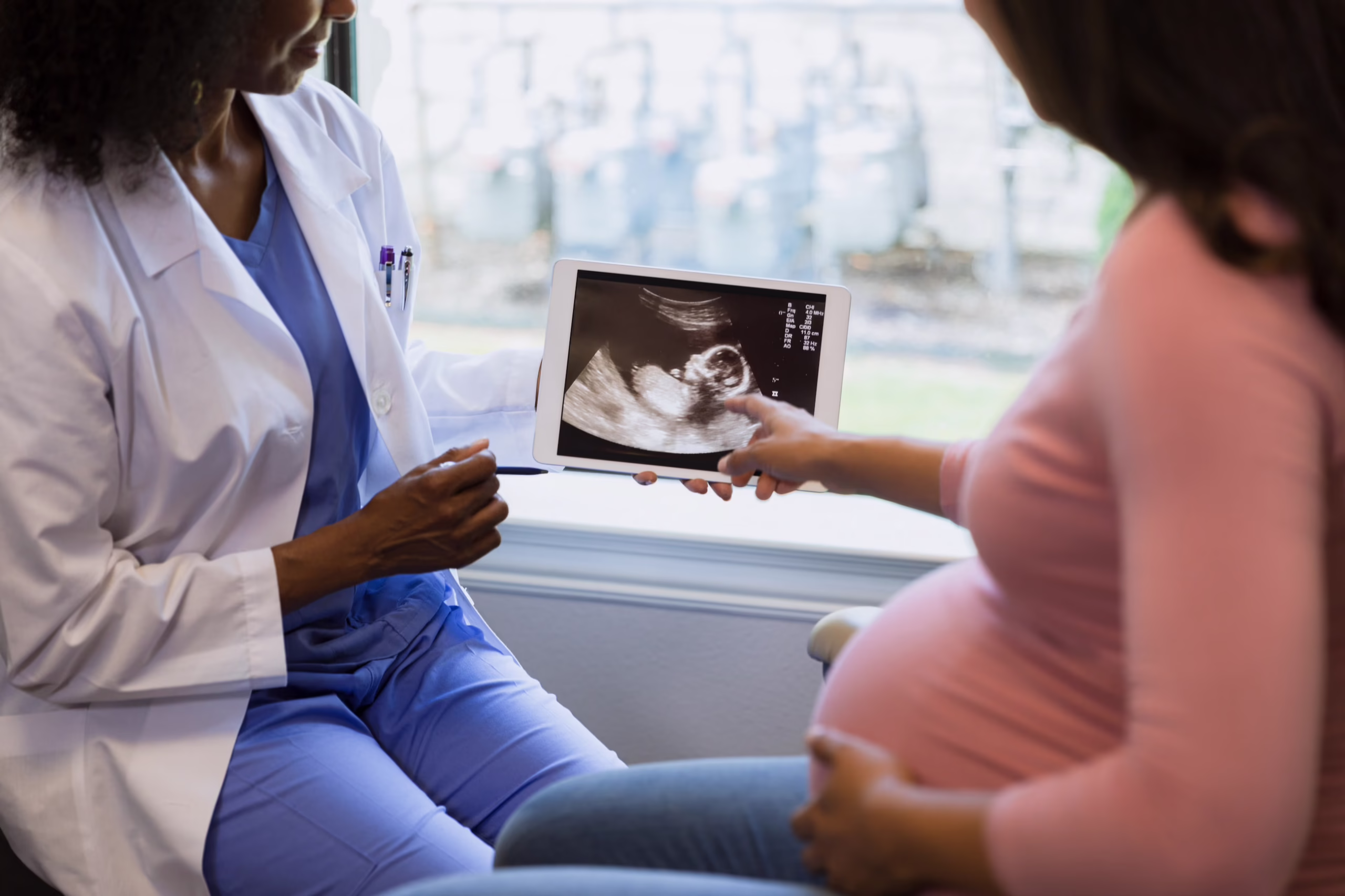 A female healthcare provider looks at a sonogram with a pregnant patient